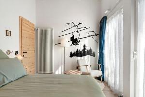a bedroom with a bed with a branch and a chair at Appartamento La Téza in Lavarone