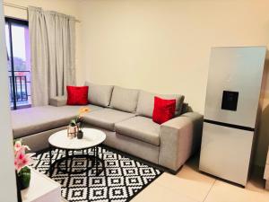 ein Wohnzimmer mit einer grauen Couch und roten Kissen in der Unterkunft Cozy getaway in Midrand