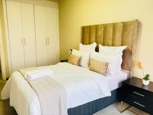 ein Schlafzimmer mit einem großen Bett mit weißen Laken und Kissen in der Unterkunft Cozy getaway in Midrand