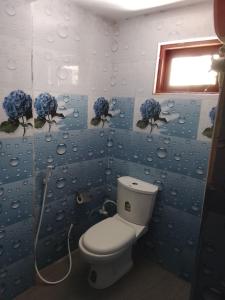 a blue bathroom with a toilet and flowers on the wall at Sana Studio in Weligama +1 photo