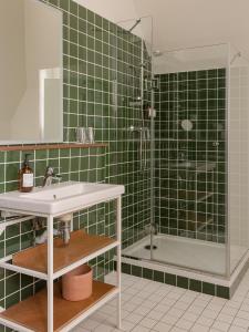 a green tiled bathroom with a sink and a shower at Alfred Hotels Toulouse Centre Wilson in Toulouse