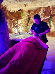 een man zittend op een bed voor een bad bij La Bess'itude in Besse-sur-Issole