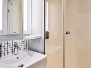 a white bathroom with a sink and a shower at ibis budget Saint-Maurice in Saint-Maurice