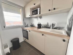 a kitchen with white cabinets and a sink and a window at Sunset View , Studio , Parking & Wifi in Villers-sur-Mer