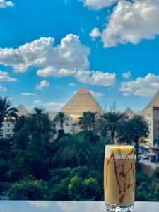 a drink sitting on a table in front of the pyramids at Saqqara Nights Hotel in Cairo