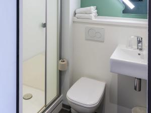 a white bathroom with a toilet and a sink at ibis budget Senlis in Senlis