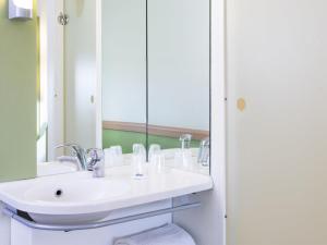 a bathroom with a white sink and a mirror at ibis budget Roissy CDG Paris Nord 2 in Roissy-en-France +49 photos