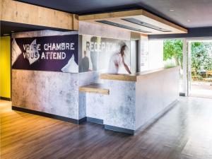 a lobby with a counter with a poster on the wall at ibis budget Vannes in Vannes