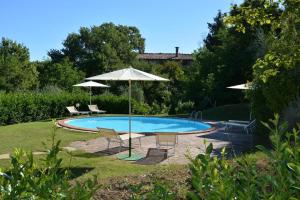 una piscina con dos sillas y una sombrilla en Monolocale, en Radicondoli 19 fotos más