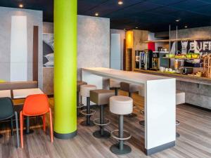 a restaurant with a bar with stools and a green pole at ibis Budget Courbevoie Paris La Défense in Courbevoie
