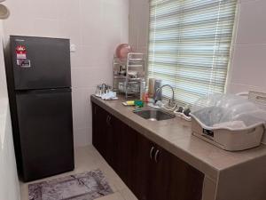 a kitchen with a black refrigerator and a sink at Lakeville Inn in Seri Iskandar