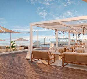 Una terraza con muebles blancos y vista al mar. en Amare Beach Hotel Sancti Petri - Adults Recommended, en Chiclana de la Frontera