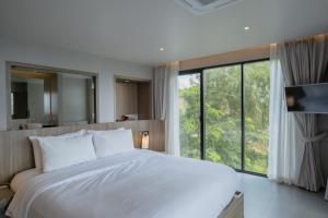 Un dormitorio con una cama blanca y una ventana grande. en Mobu Chiang Rai, Thailand, en Ban Sam Laem