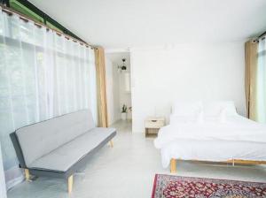 a white bedroom with a bed and a couch at Casa Ya Thip in Ban Huai Ti