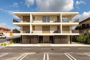 Urban Lodge- Appartamenti in Franciacorta في إيربوسكو: عمارة سكنية مع شرفة وموقف سيارات