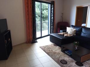 a living room with a black couch and a table at Casa Mao-Cheia in Arco da Calheta +18 photos
