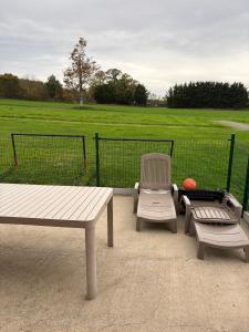 trois tables et chaises de pique-nique avec un champ en arrière-plan dans l'établissement Le Chêne, à Baguer-Pican