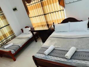 a bedroom with two beds and a desk in it at Ella Bungalow in Ella