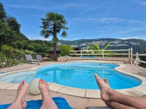 une personne se posant au bord d'une piscine avec les pieds en haut dans l'établissement La Corbassière, à Murs-et-Gélignieux