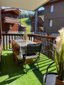 a patio with a table and chairs on the grass at Le Portail 76 in Valmorel