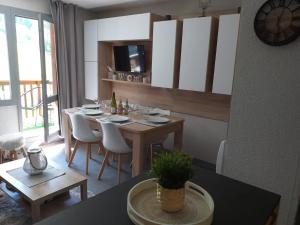 a dining room with a table with white chairs at Le Portail 76 in Valmorel +2 photos
