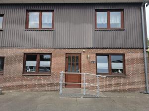 a brick building with a brown door and windows at Schöne Monteurs Wohnung 6 in Wesseln