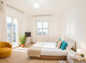 een witte slaapkamer met een bed en een gele stoel bij Perla d'aMare in San Lorenzo al Mare