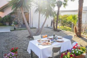 een witte tafel met eten en drinken erop met palmbomen bij Perla d'aMare in San Lorenzo al Mare