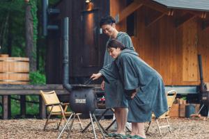 Zwei Personen stehen um einen Grill in einem Garten herum. in der Unterkunft Earthboat Nasu in Nasu