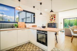 a kitchen with white cabinets and a wooden counter top at Belle maison moderne proche plages & bourg in Carnac