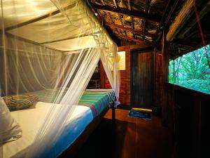 una cama con dosel en una habitación con ventana en Jungle Host Hostel And Tree House, en Sigiriya