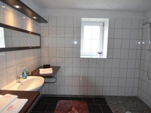 ein weiß gefliestes Bad mit einem Waschbecken und einem Fenster in der Unterkunft schönes Ferienhaus in ruhiger Lage, Spreewald, Brandenburger Seen in der Nähe in Schenkendöbern