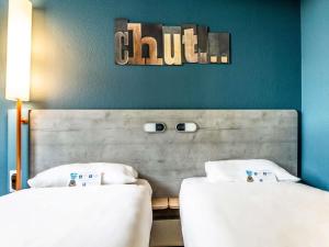 two beds sitting next to each other in a room at ibis budget Pertuis Portes du Luberon in Pertuis