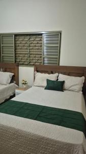 a bedroom with a large white bed with green sheets at Rancho com acesso direto ao rio, área verde e lazer completo in Santa Fé do Sul