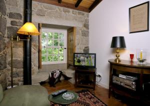 sala de estar con TV y pared de piedra. en Castelo Do Castro, en Carrazedo