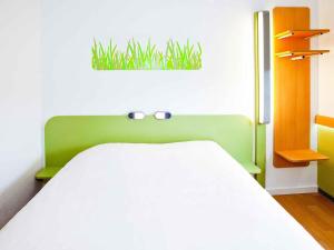 1 dormitorio con 1 cama con una planta en la pared en ibis budget Metz Technopole, en Metz