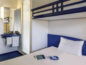 Una habitación con una cama, un ordenador portátil y auriculares. en ibis budget Metz Technopole, en Metz