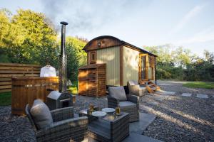 a small cabin with a couch and chairs and a tv at Cwtch Ffynnone Luxury Shepherds Hut in Newchapel