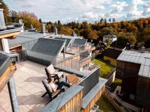 una mujer sentada en un balcón de una casa en OpenSky Wörthersee Lodge, en Pörtschach am Wörthersee
