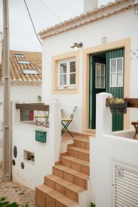 a white house with a green door and stairs at Casa Roma in Raposeira