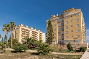 two tall buildings with trees and palm trees at Beachfront penthouse in La Manga in San Blas