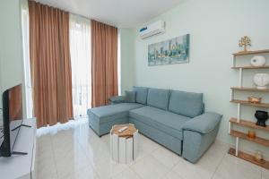 a living room with a blue couch and a tv at Luxury Apartment with Parking in Tirana
