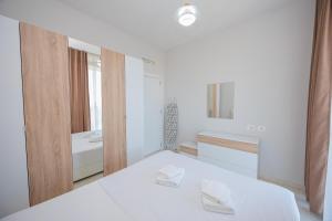 a white room with a bed and a mirror at Luxury Apartment with Parking in Tirana