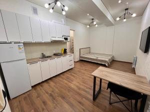 a kitchen with white cabinets and a wooden table at Apartment in the center in Bishkek