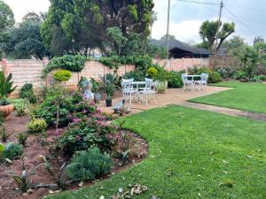 a garden with white chairs and flowers in a yard at Highway Haven in Stilfontein +10 photos