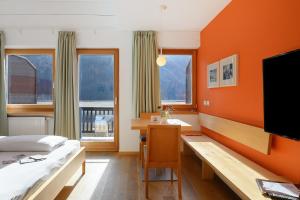 a hotel room with a bed and a desk and a television at Kreativ Hotel Landhaus Schweigl in Ultimo