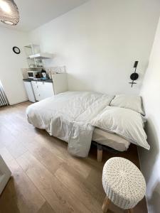 een witte slaapkamer met een bed en een kruk bij Studio au cœur de Chabeuil in Chabeuil +3 foto's