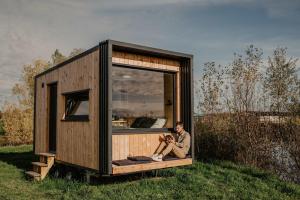 a man sitting in a tiny house in a field at Homnest - Loge insolite au coeur d'un ranch - Balade à cheval in Espinasse-Vozelle
