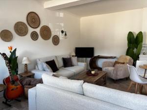 a living room with a white couch and a guitar at Bracken Cottage in Weymouth