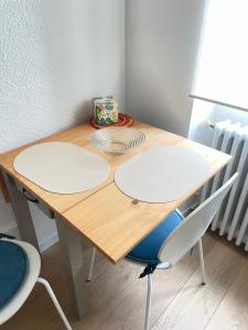 een houten tafel met twee witte platen erop bij Studio au cœur de Chabeuil in Chabeuil